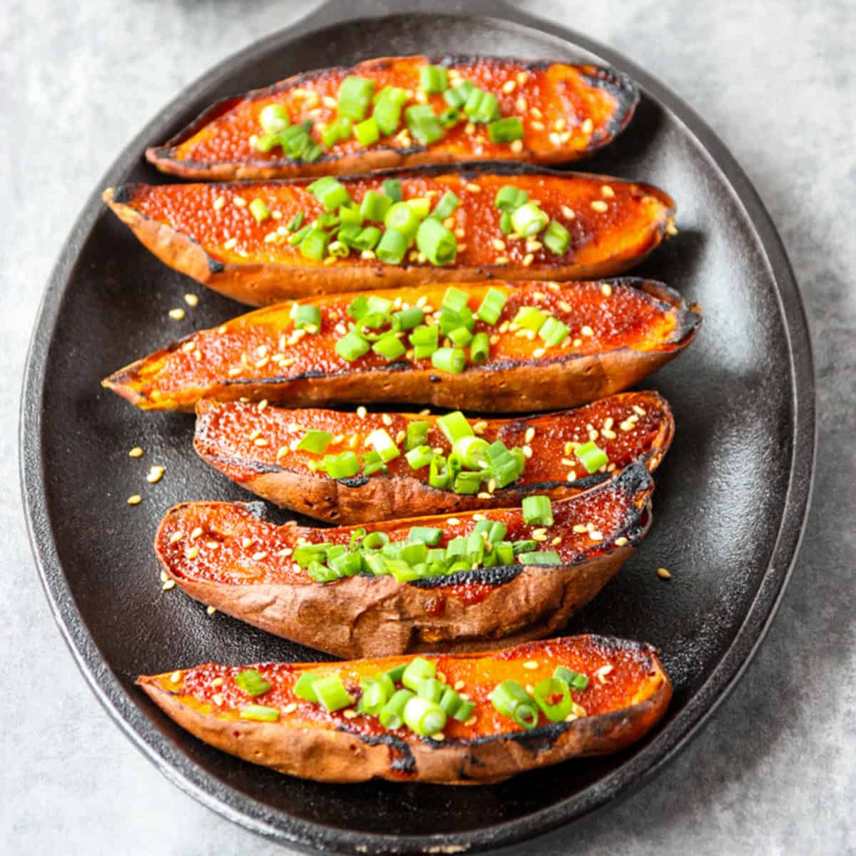 Miso baked sweet potatoes on a black platter.