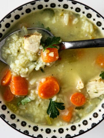 Turkey and rice soup in a black and white bowl.